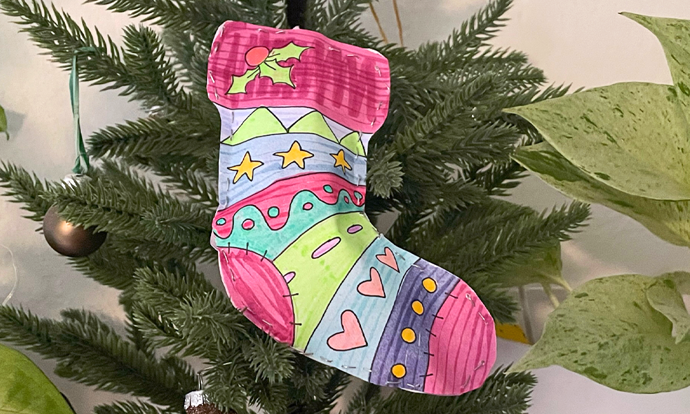 Puffy paper holiday sock on Christmas tree with ornaments and other plants