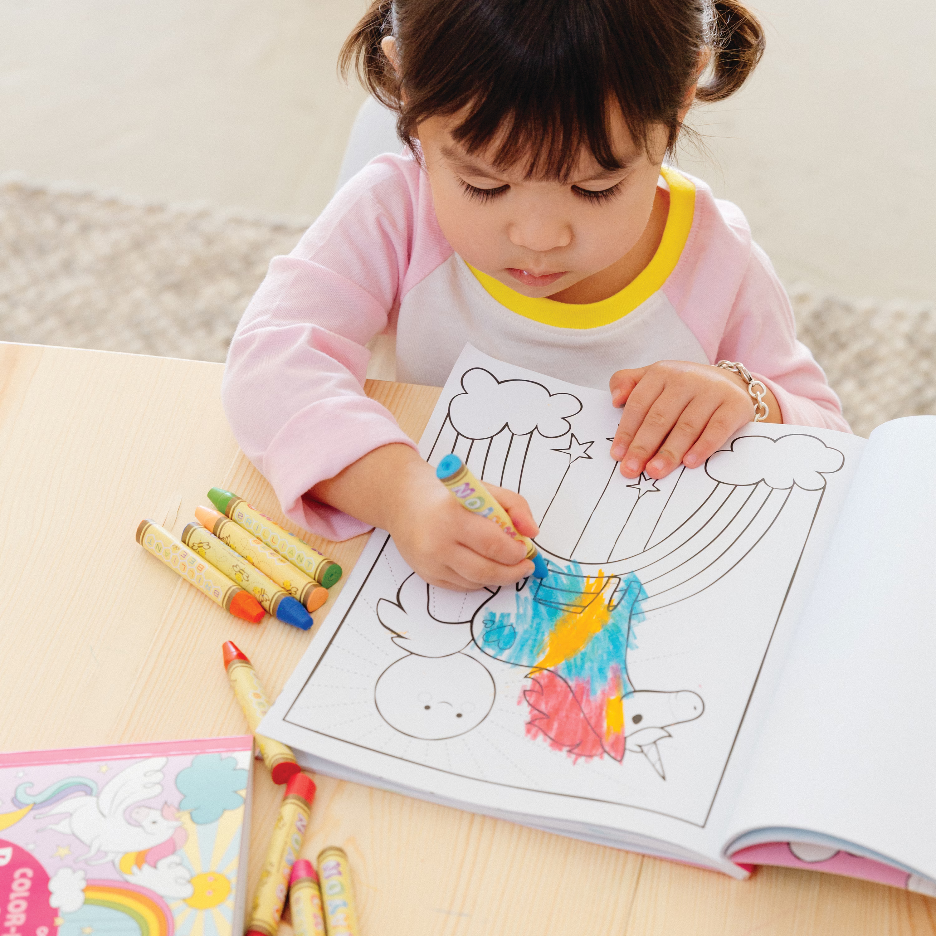 Kid coloring in Enchanted Unicorns Coloring Book with beeswax crayons