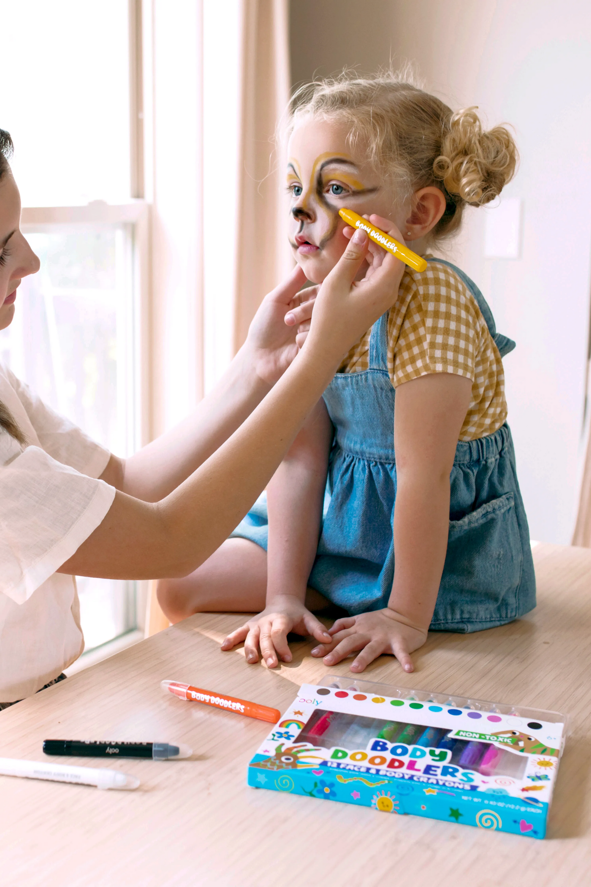 Mother drawing animal face with OOLY Body Doodlers - Face & Body Crayons on little girl