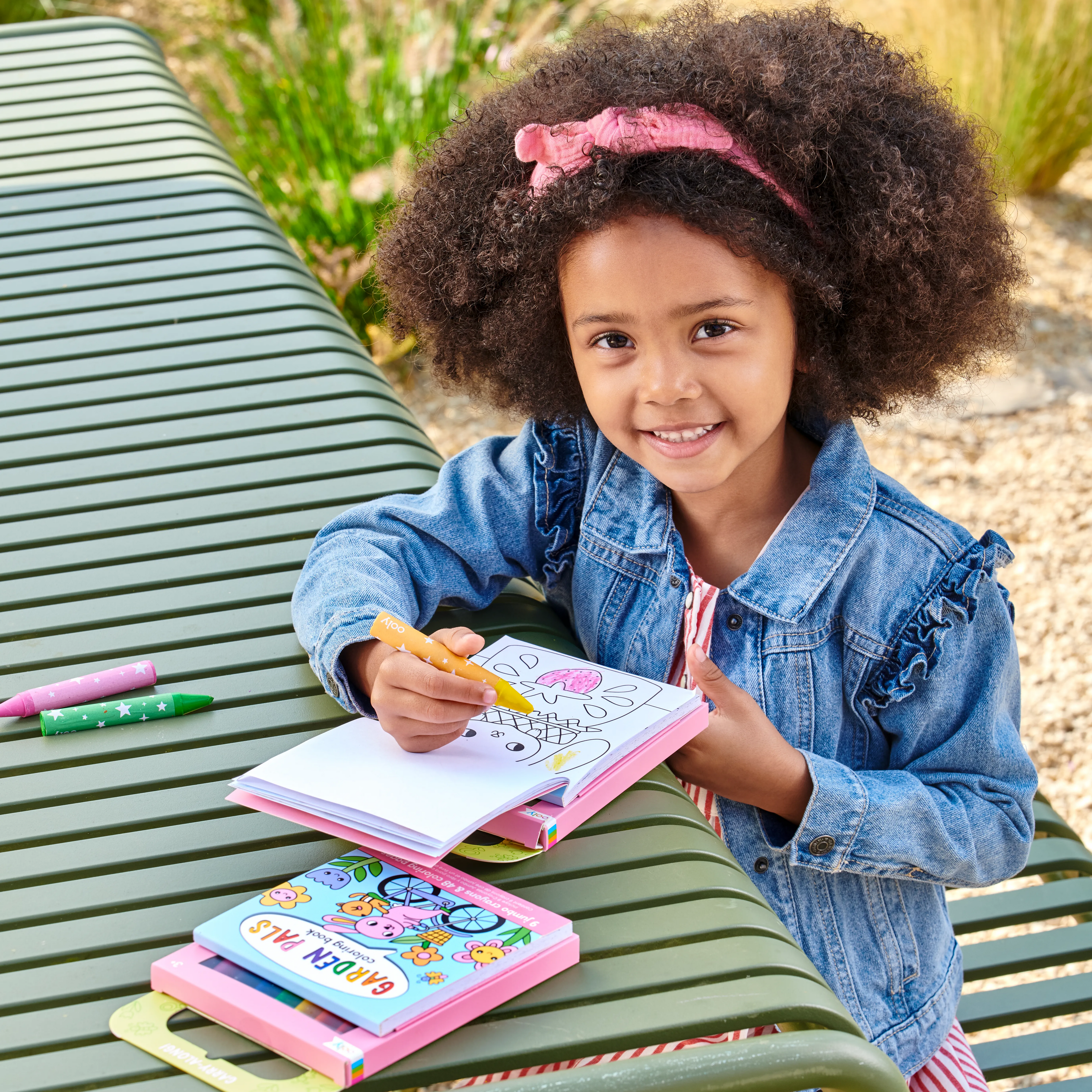 Girl on park bench coloring a page from a set of Carry Along! Coloring Book and Crayon Set - Garden Pals