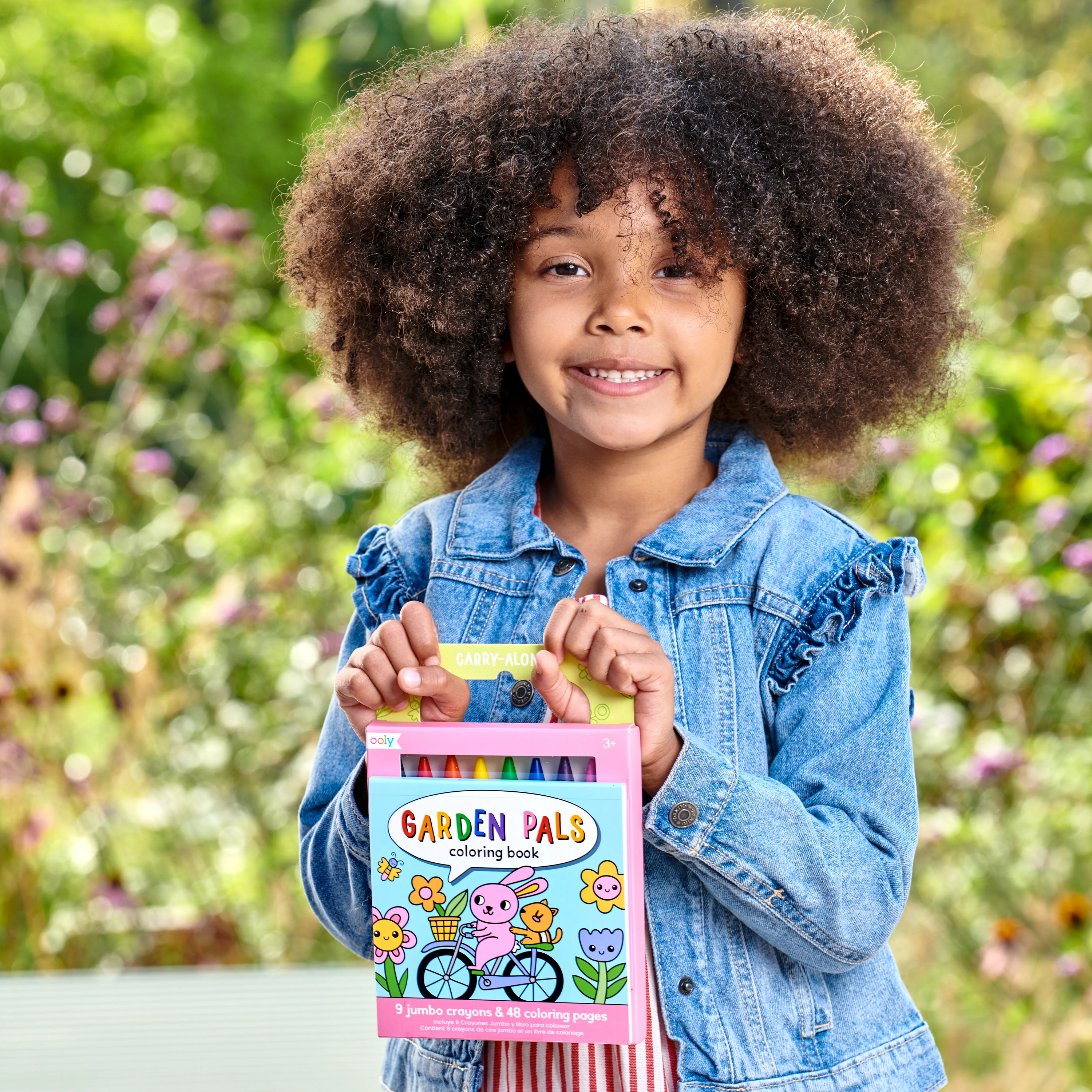 Girl holding a set of Carry Along! Coloring Book and Crayon Set - Garden Pals in a park