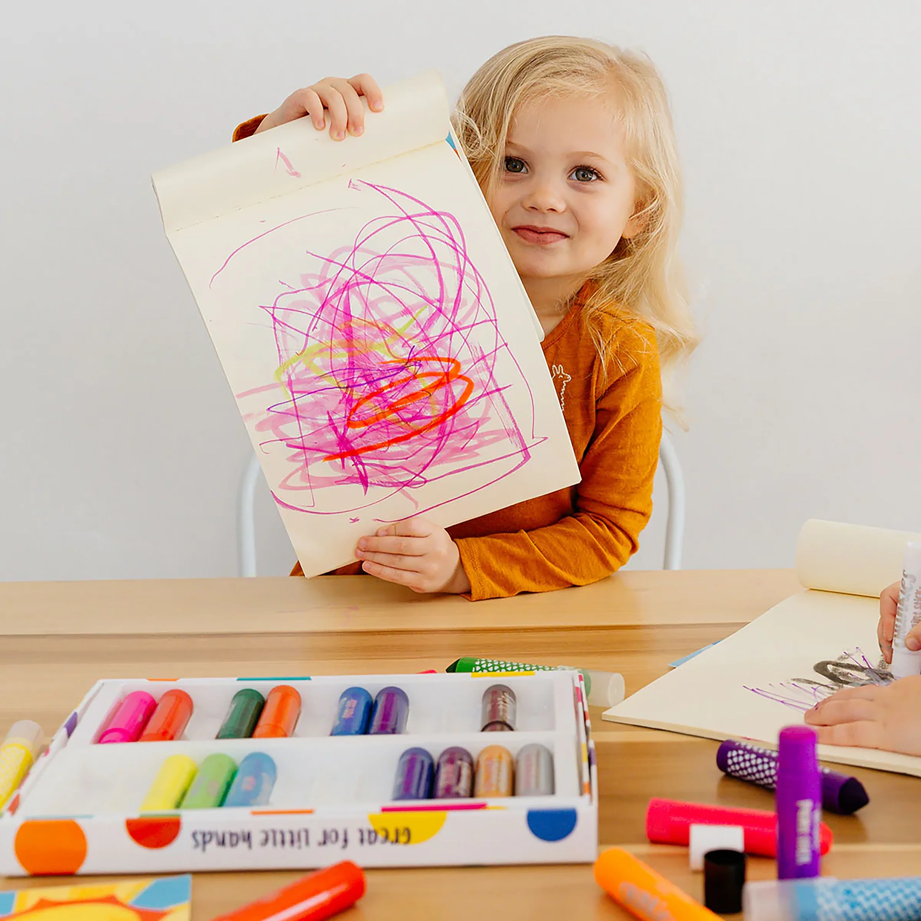 Girl holding up painting made with pink, orange and yellow paint from Chunkies Paint Sticks Variety Pack