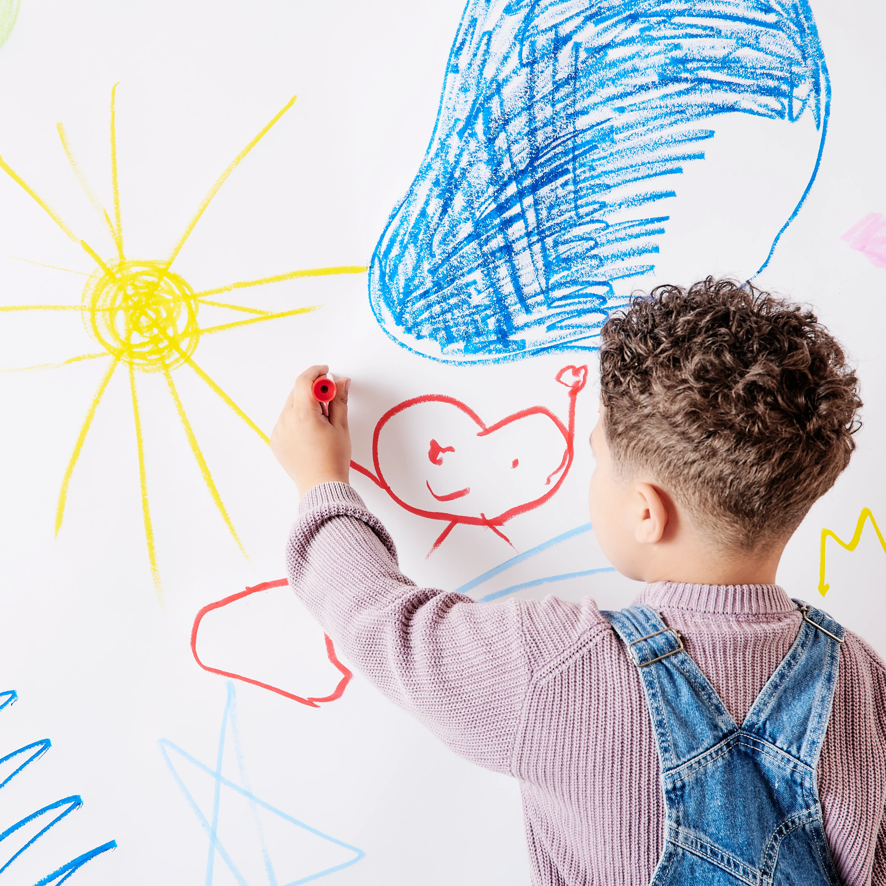 Boy painting a sun and happy heart with OOLY Chunkies paint sticks