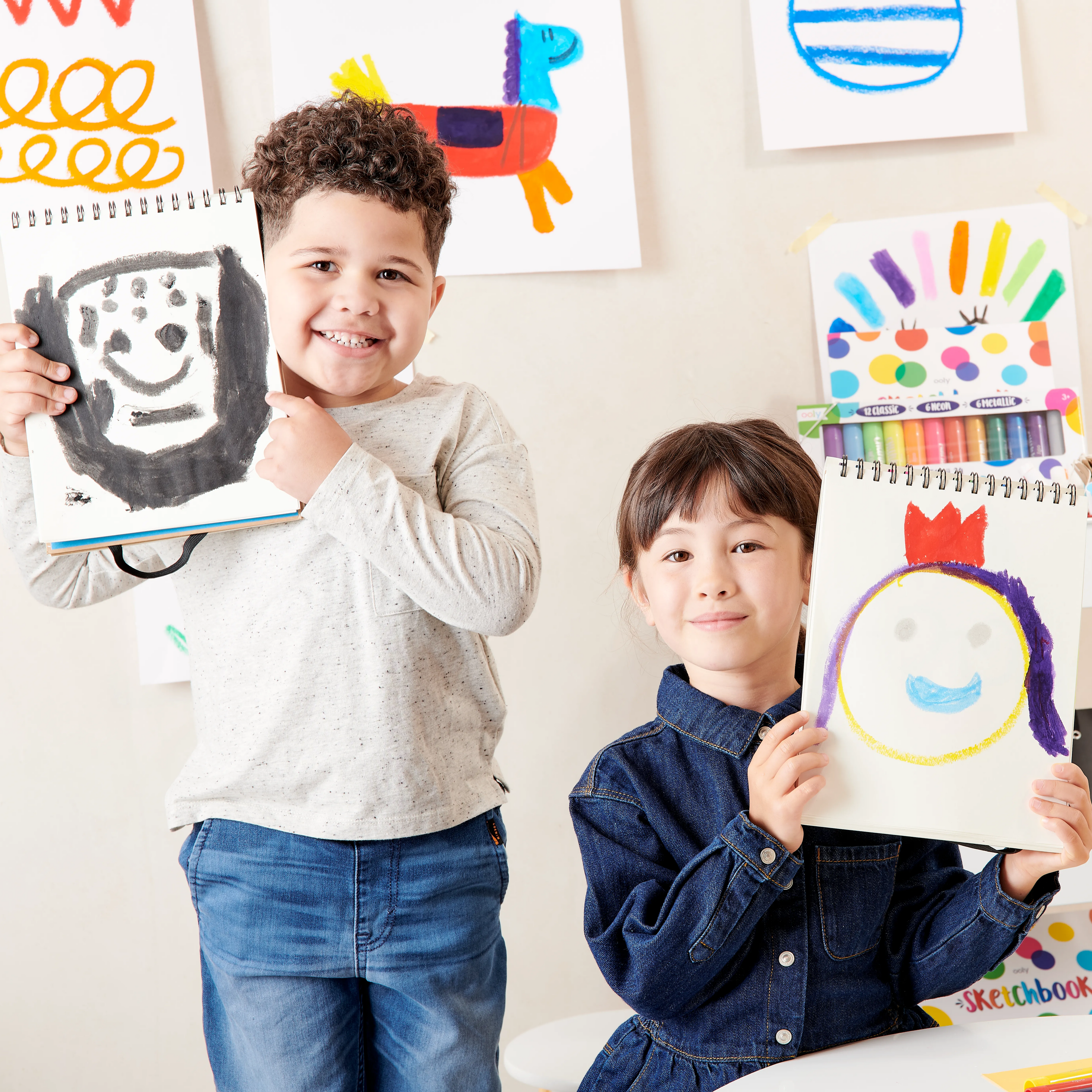 Two kids holding up completed paintings made with OOLY Chunkies paint sticks