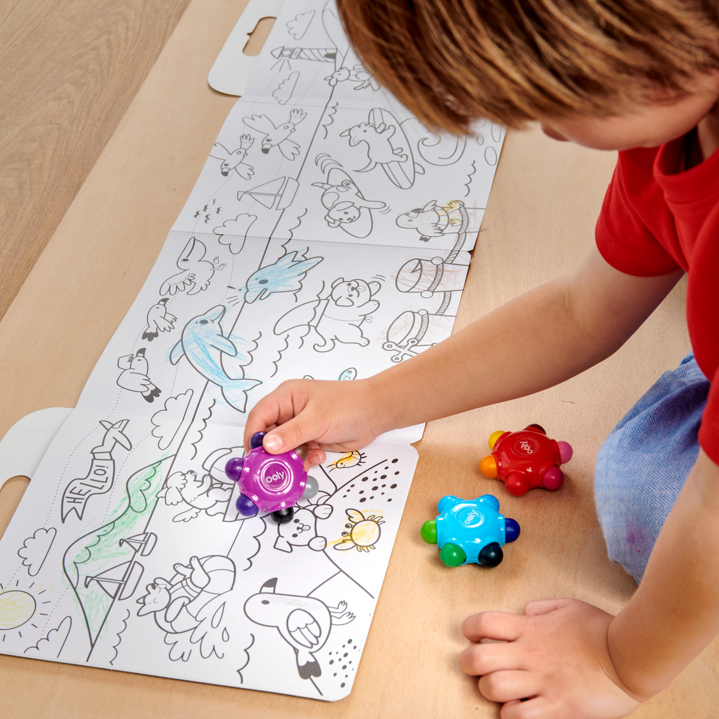 Boy coloring in large panoramic coloring book with OOLY Color Burst Crayons