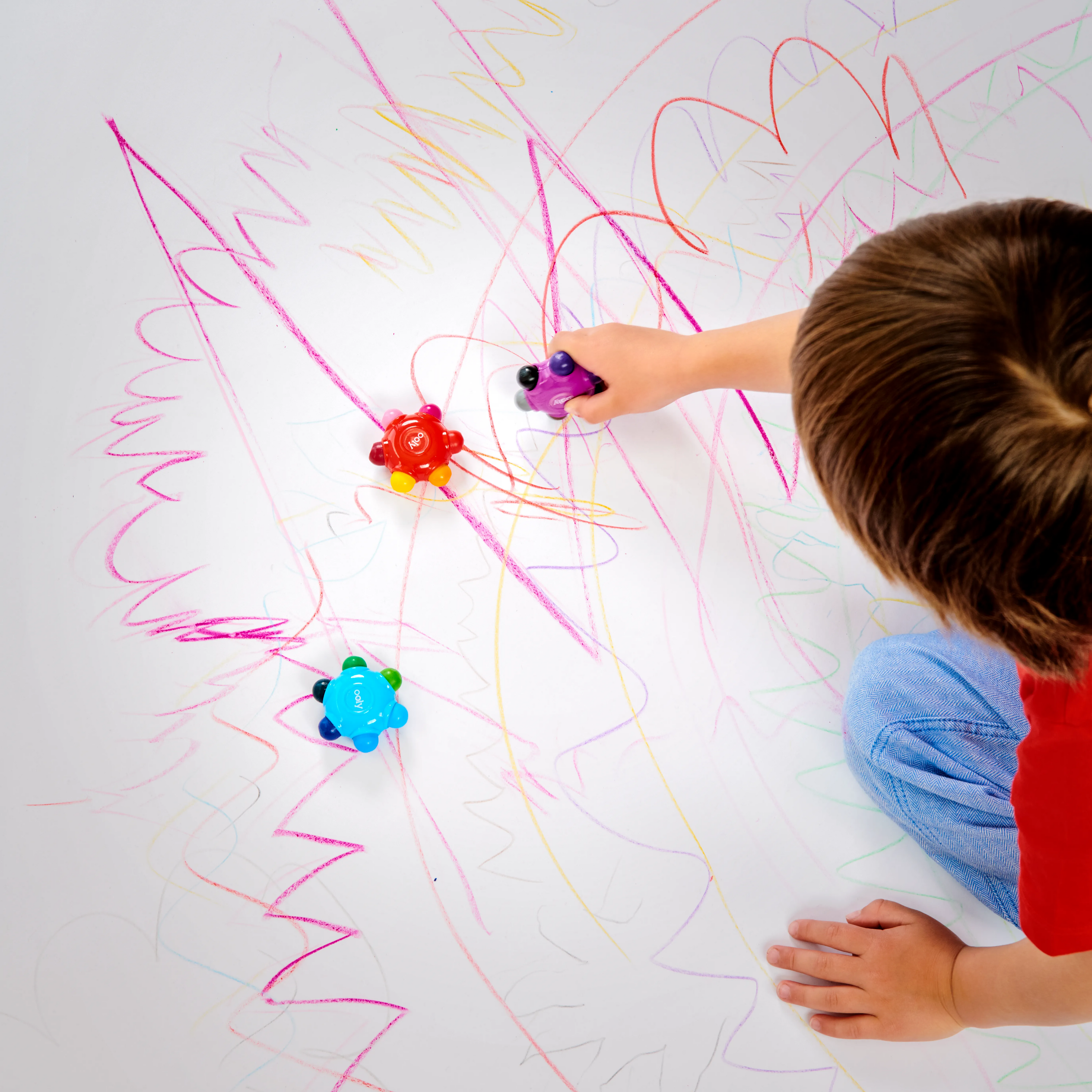 Boy coloring on very large white paper with OOLY Color Burst Crayons