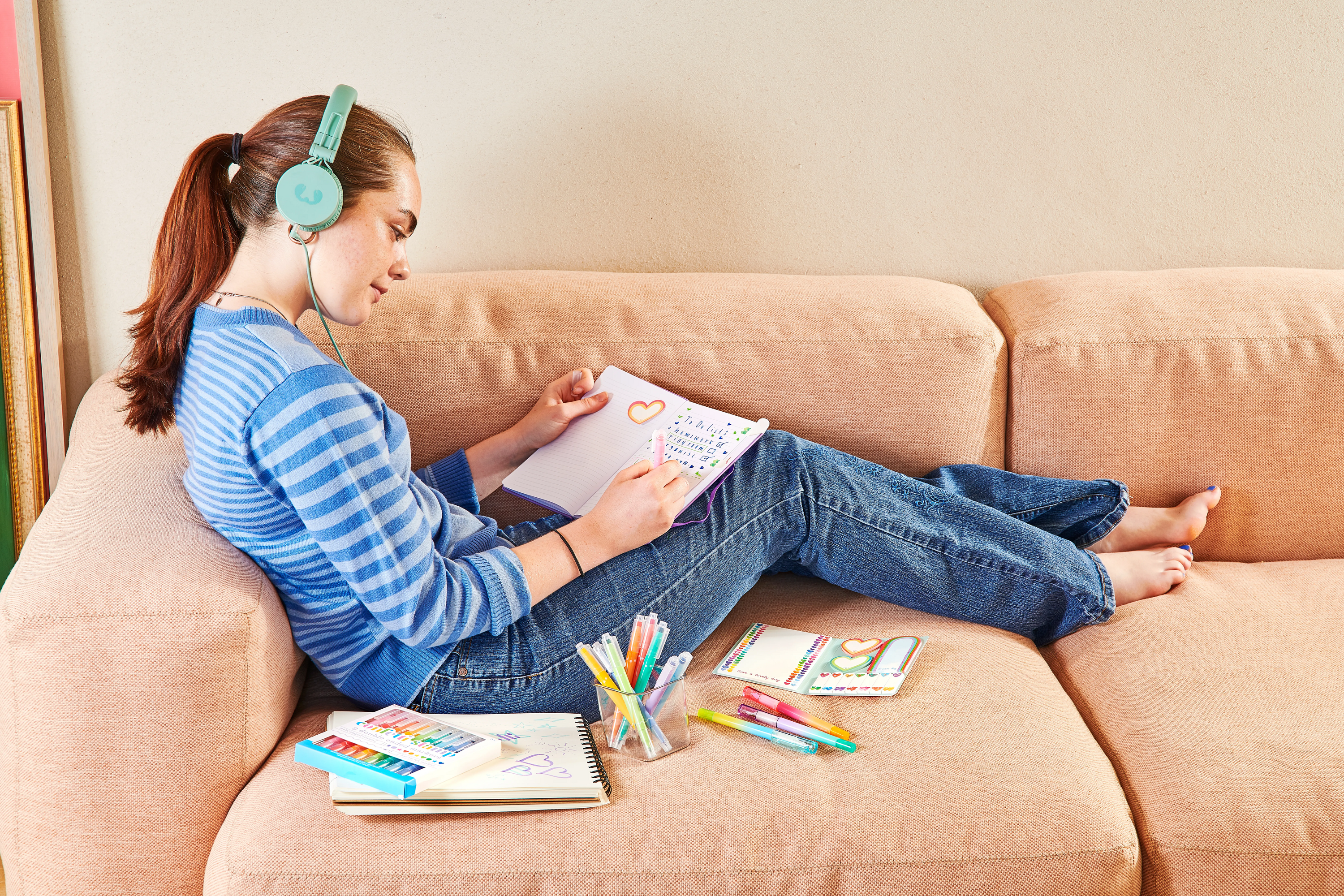 Girl on couch updating a planner with OOLY Confetti Stamp Double-Ended Markers