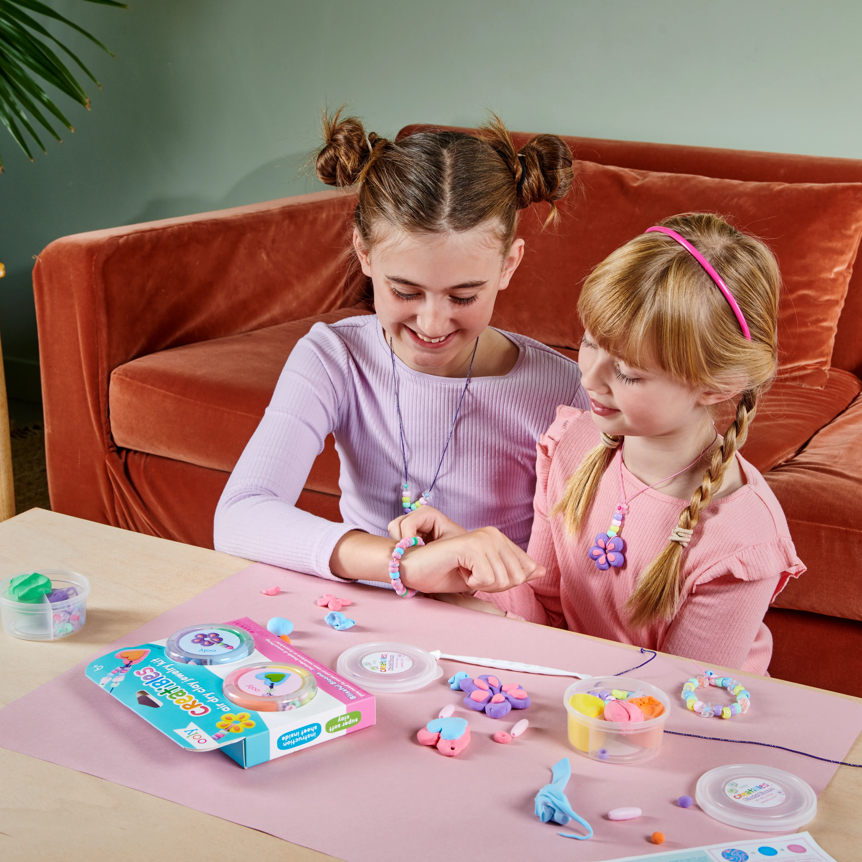 Two girls with finished necklaces and bracelets from the OOLY Creatibles Air Dry Clay Jewelry Kit - Blissful Blooms set 