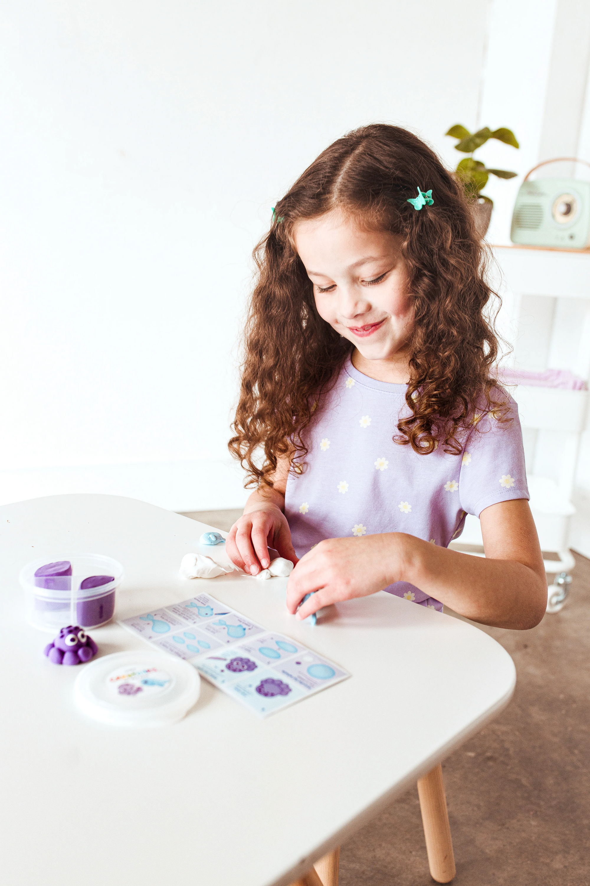 Girl smiling while making animals from OOLY Creatibles Mini Air Dry Clay Kit - Ocean BFFs