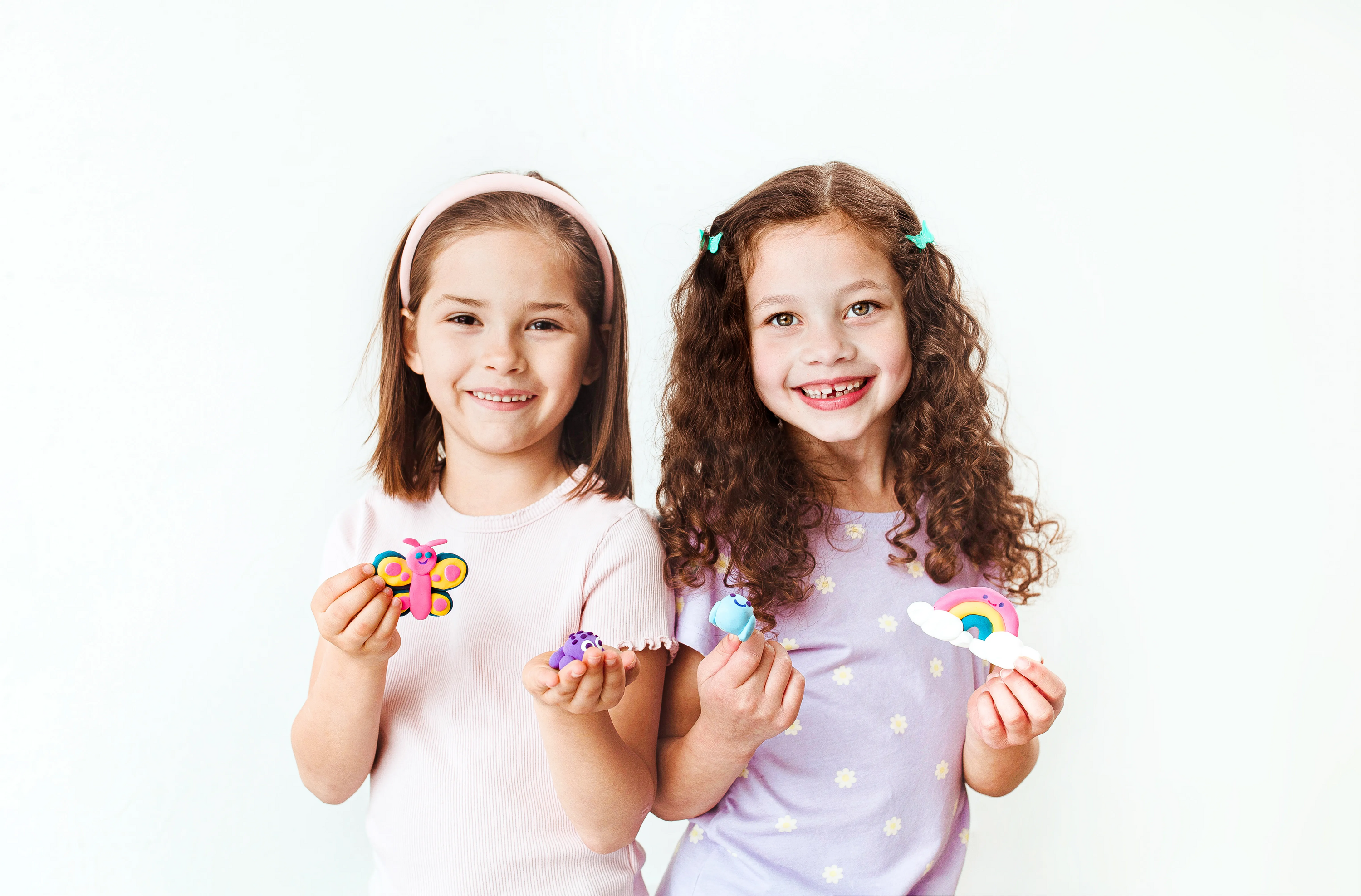 Two girls holding finished clay creations from OOLY Creatibles Mini Air Dry Clay Kit - Ocean BFFs