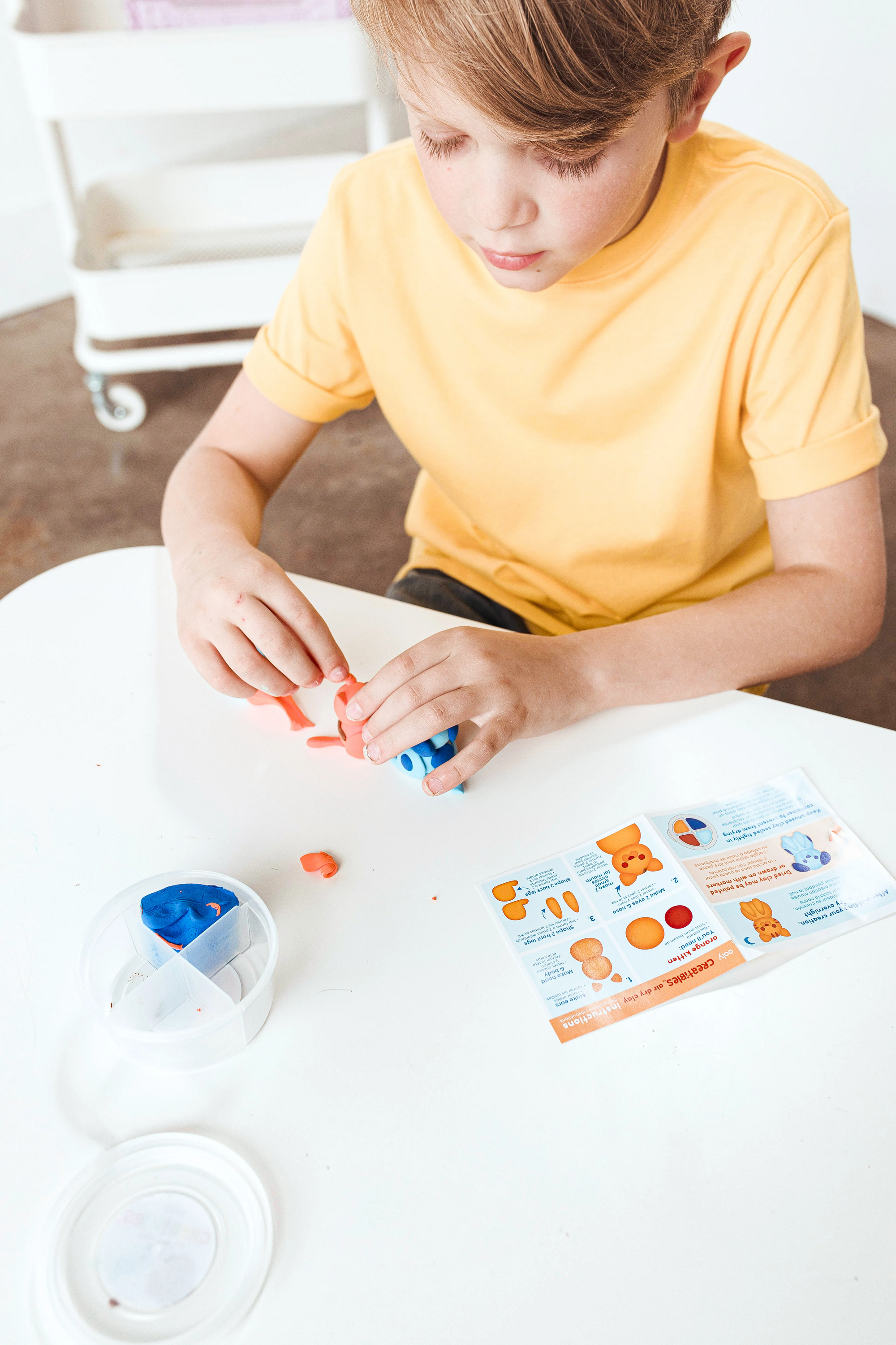 High angle of boy making clay cat and dog from OOLY Creatibles Mini Air Dry Clay Kit - Pet BFFs