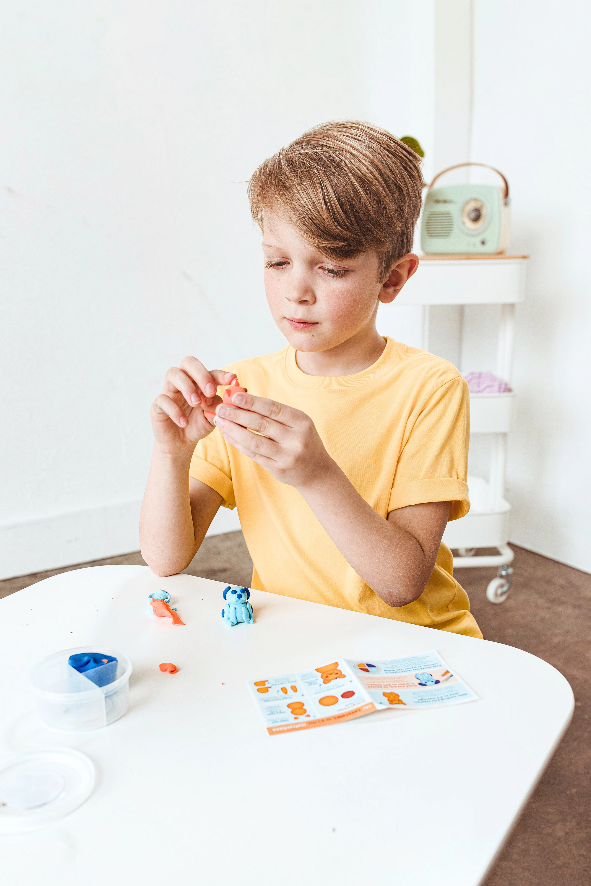 Boy making clay cat from OOLY Creatibles Mini Air Dry Clay Kit - Pet BFFs