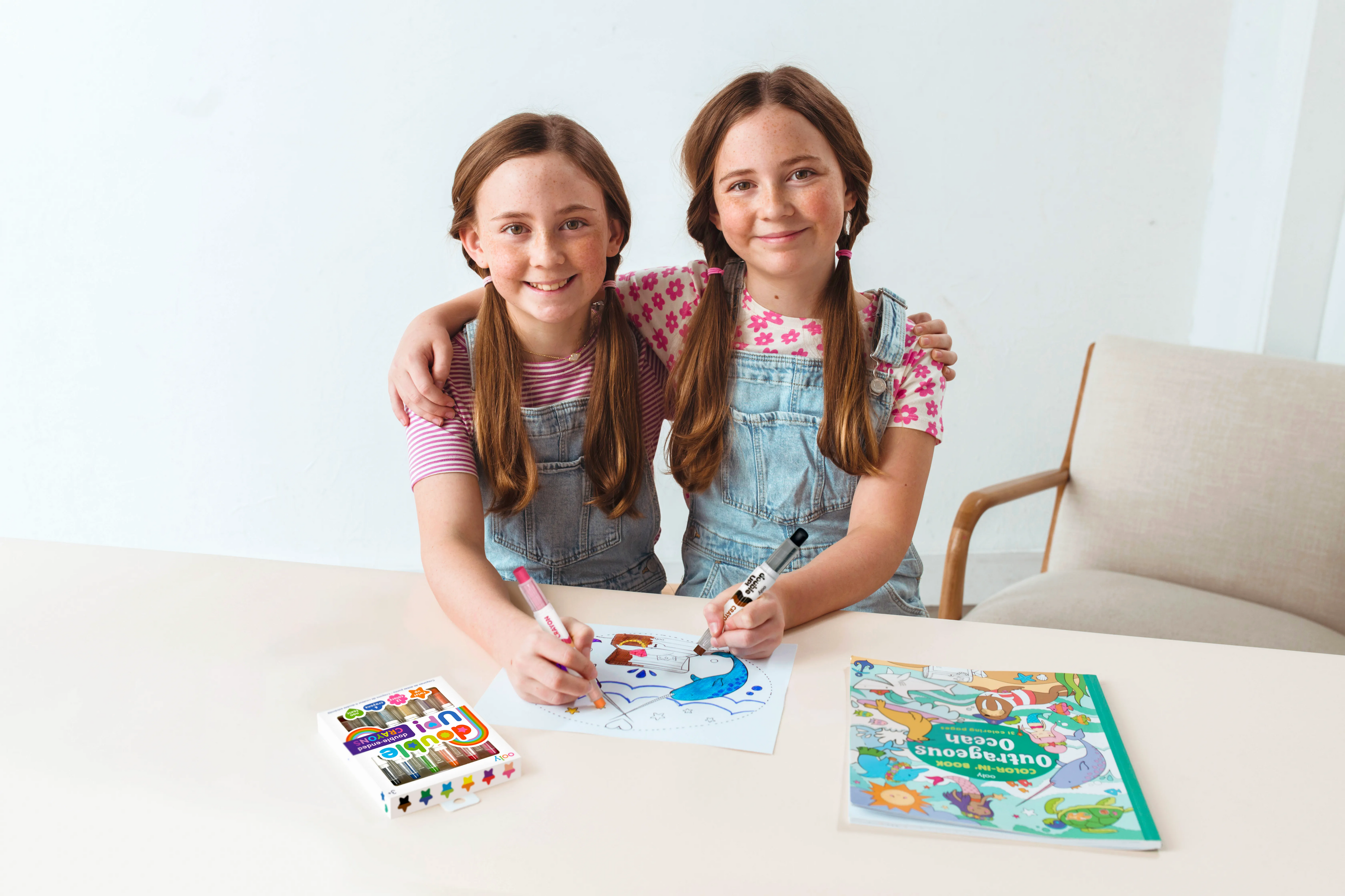 Two girls sitting close while coloring in a coloring book with OOLY Double Up! double ended crayons