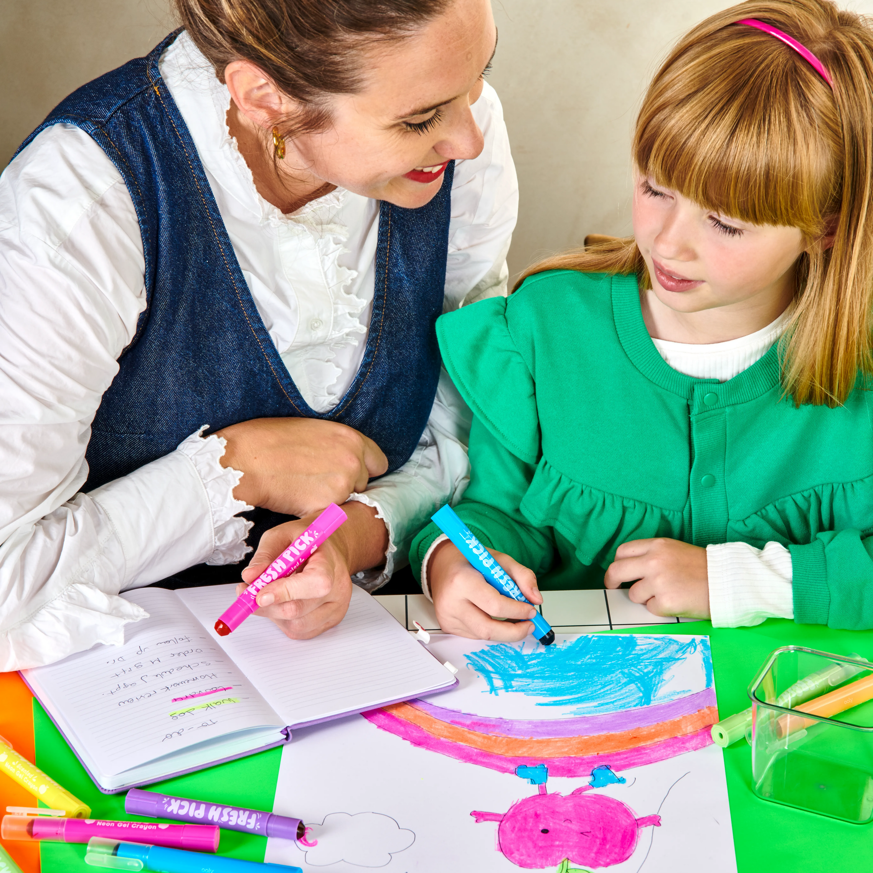 Close up of mom and daughter coloring and highlighting using OOLY Fresh Pick Apple Scented Gel Crayons