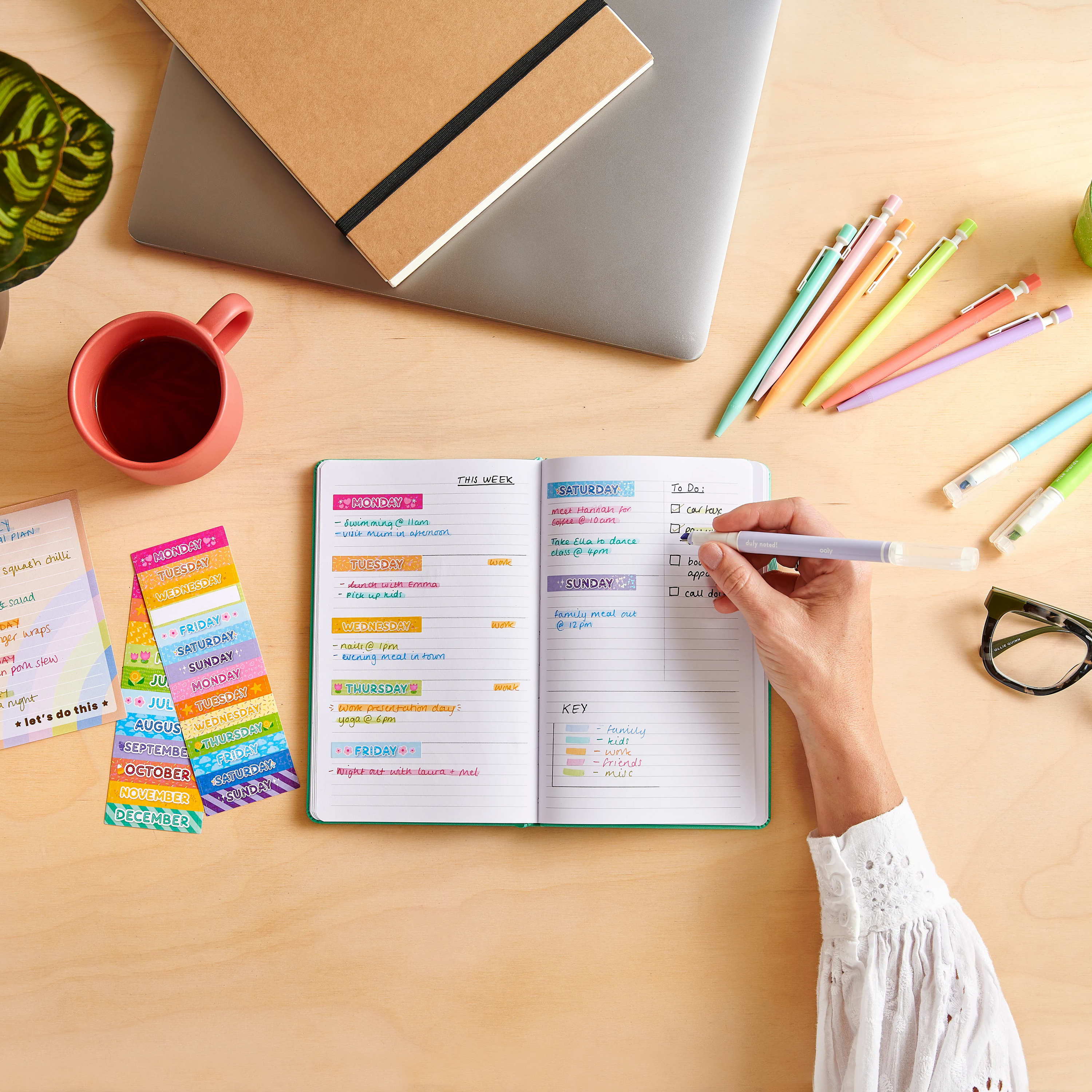 Woman writing in planner with OOLY Noted! 2-in-1 Micro Fine Tip Pen and Highlighters