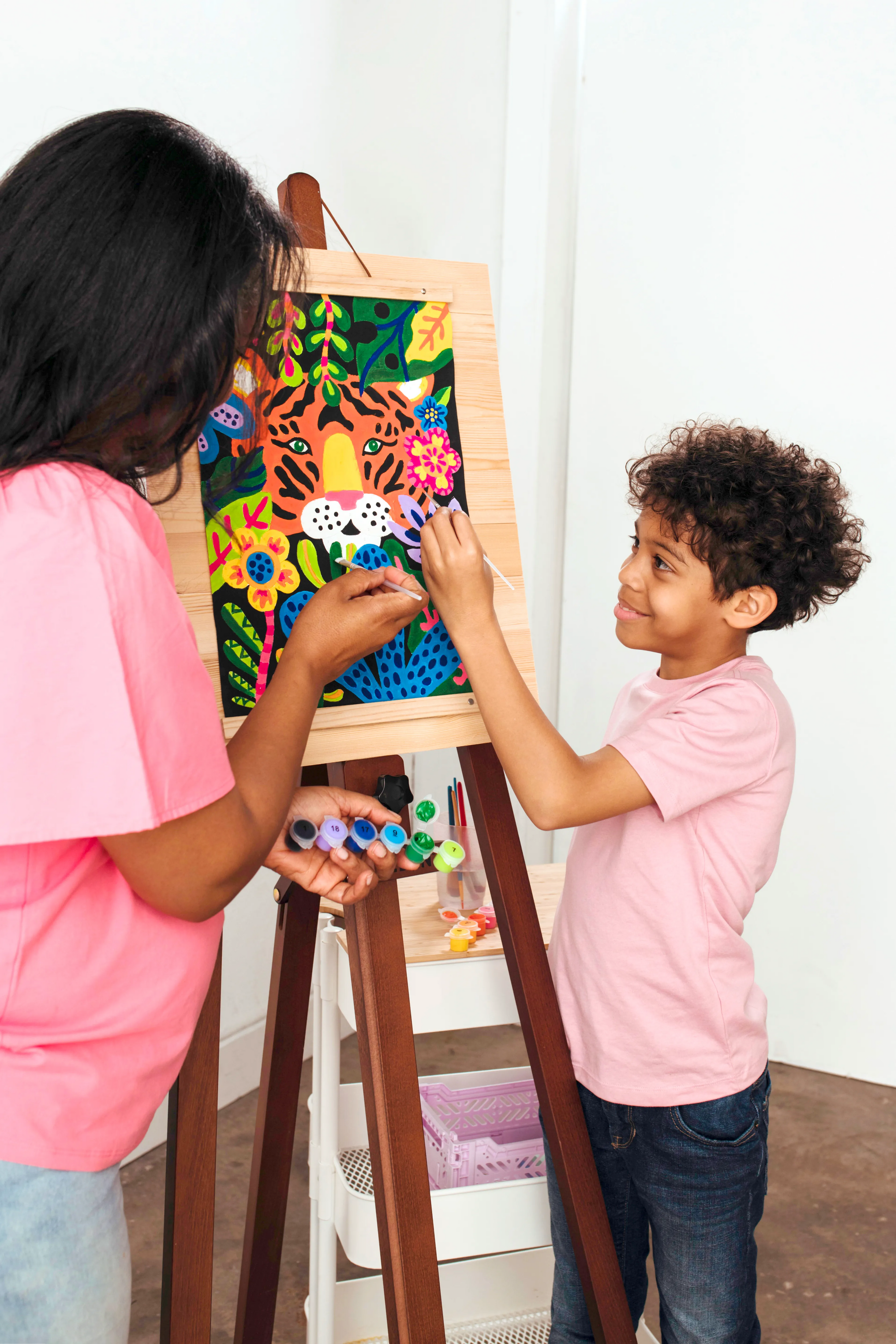 Two kids finishing canvas painting from the Paintology Paint-By-Number Canvas Kit - Tiger Eyes