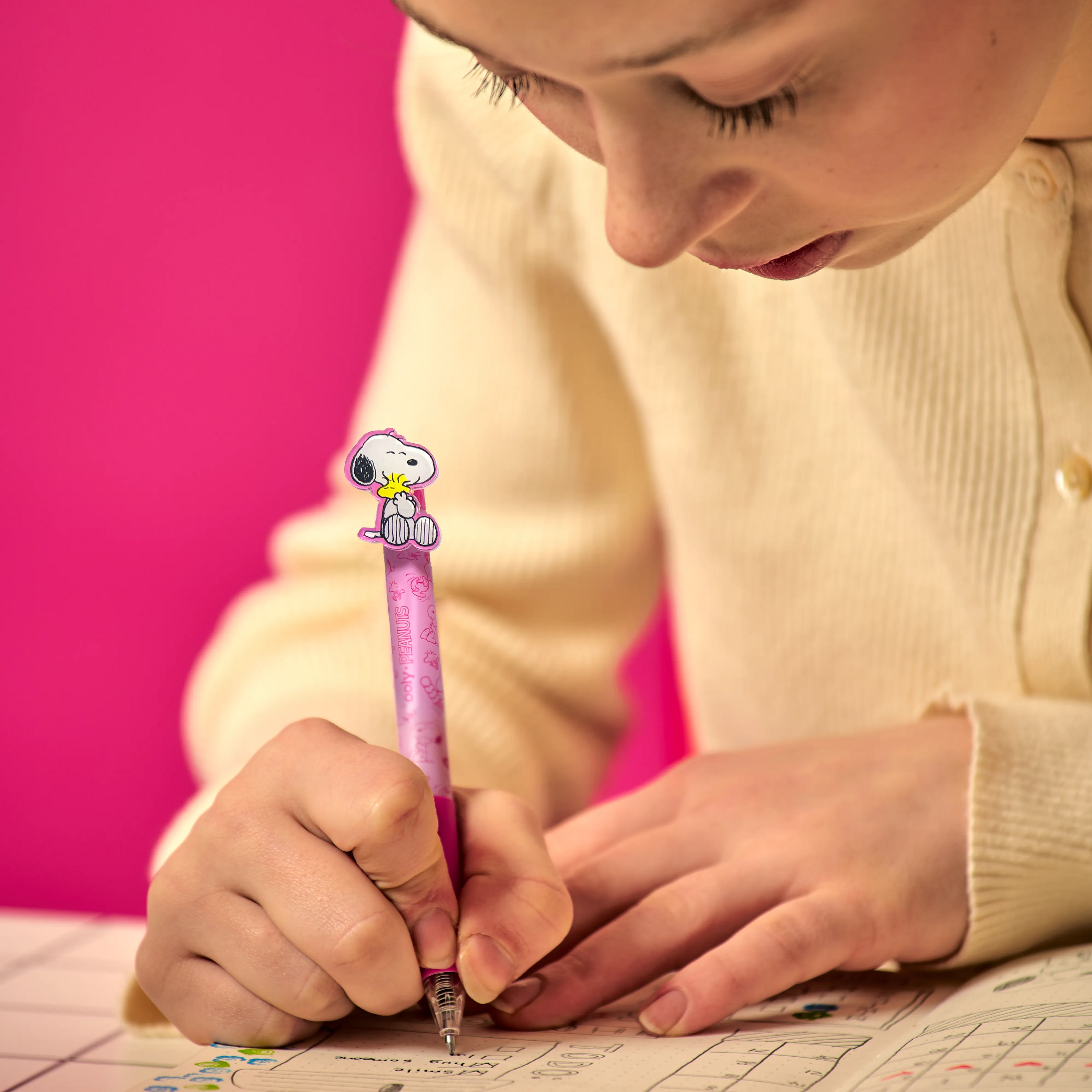 Close up of woman writing in planner using a pink black ink Snoopy gel pen from a OOLY x Peanuts - Black Ink Retractable Gel Pens set