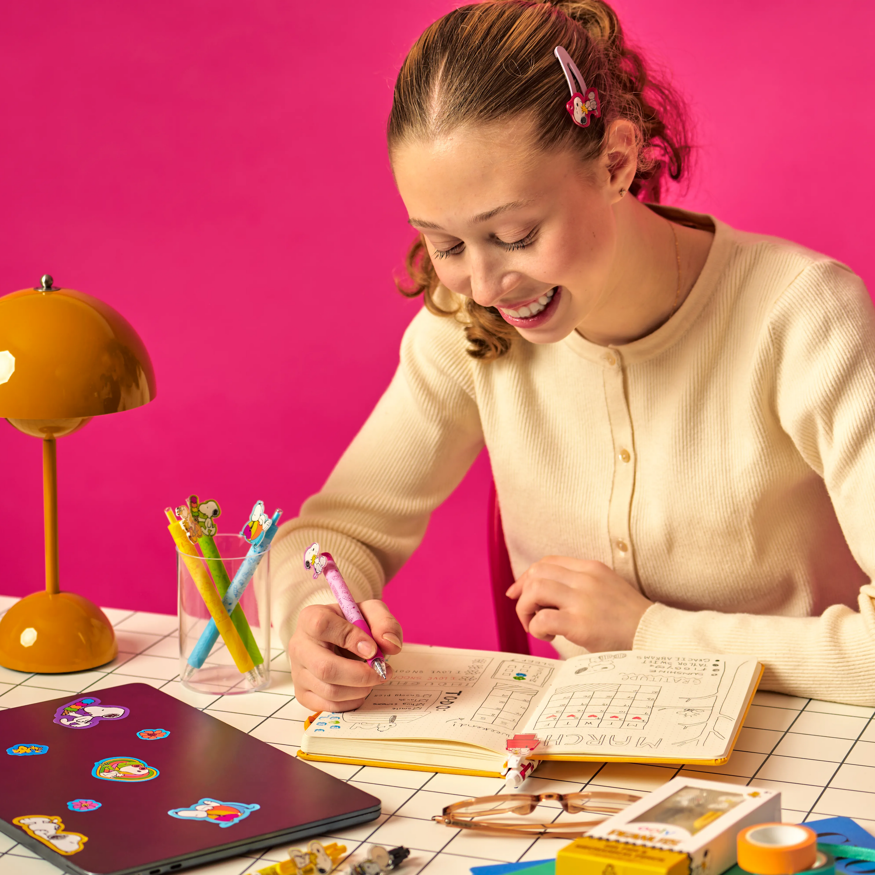 Woman writing in planner using a pink black ink Snoopy gel pen from a OOLY x Peanuts - Black Ink Retractable Gel Pens set