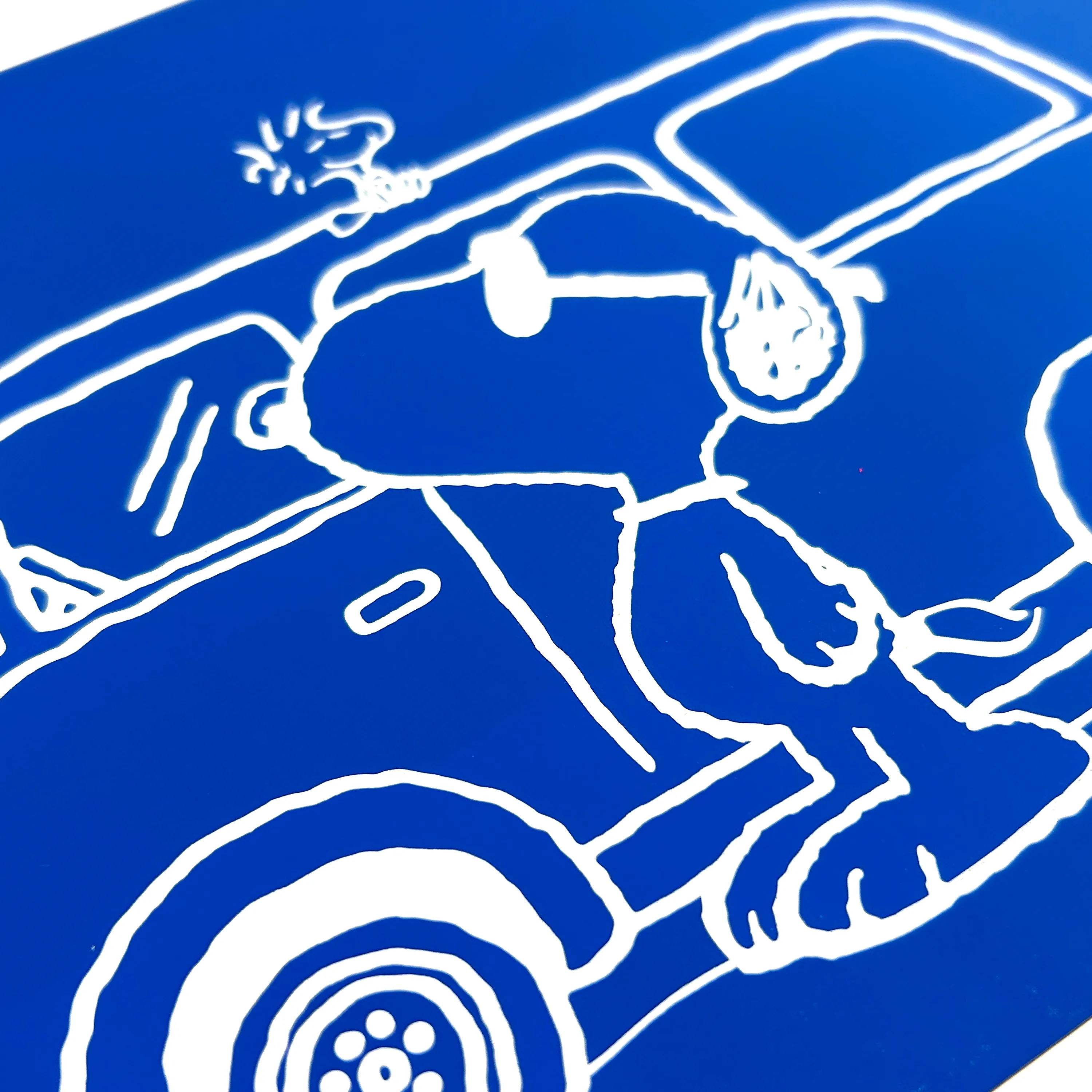 Close up of a scratch card with Snoopy and Woodstock in front of a car from the OOLY x Peanuts Scratch Art Kit