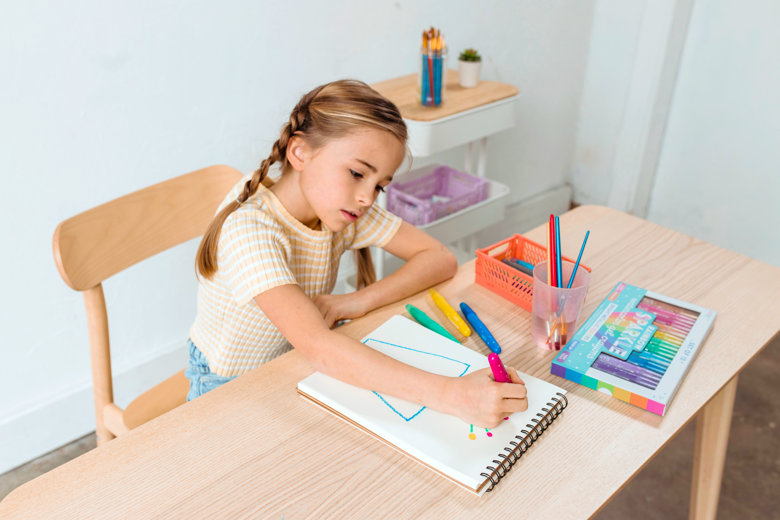 Girl coloring blue flower pot with OOLY Rainbow Sparkle Metallic Watercolor Gel Crayons