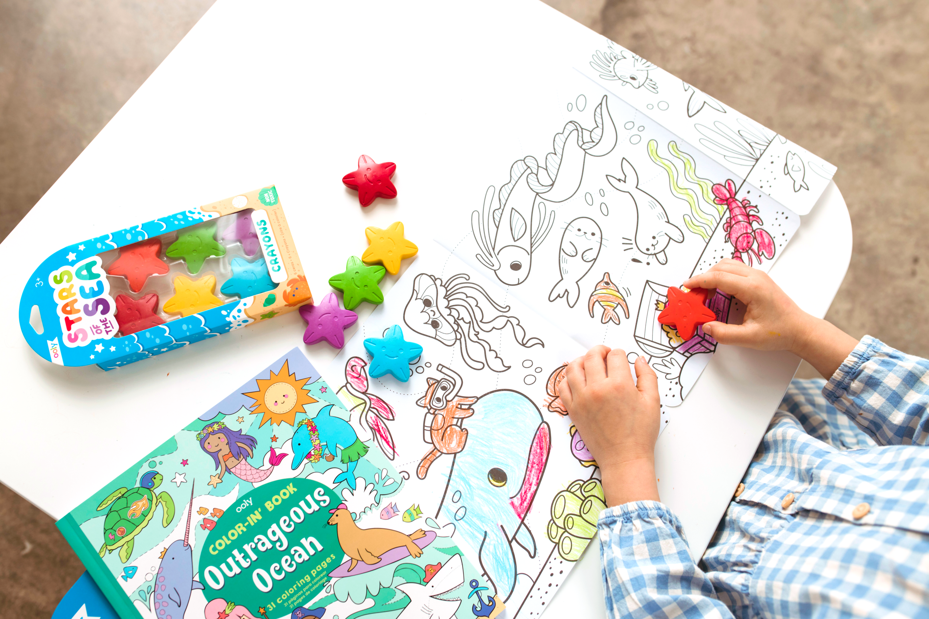 Girl coloring in Outrageous Ocean coloring book with Stars of the Sea Crayons