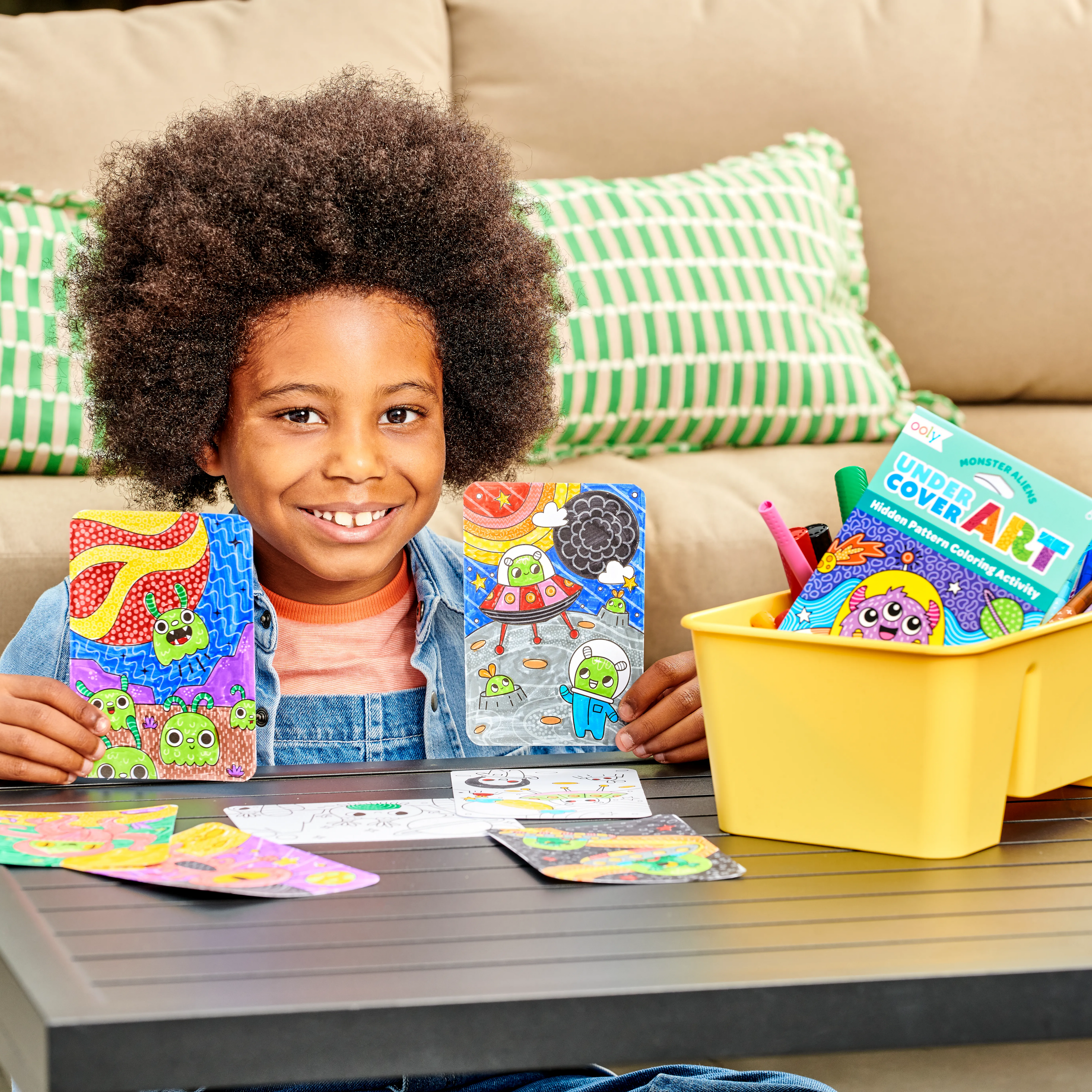 Kid holding up finished space coloring cards from OOLY Undercover Art Hidden Pattern Coloring Activity Art Cards