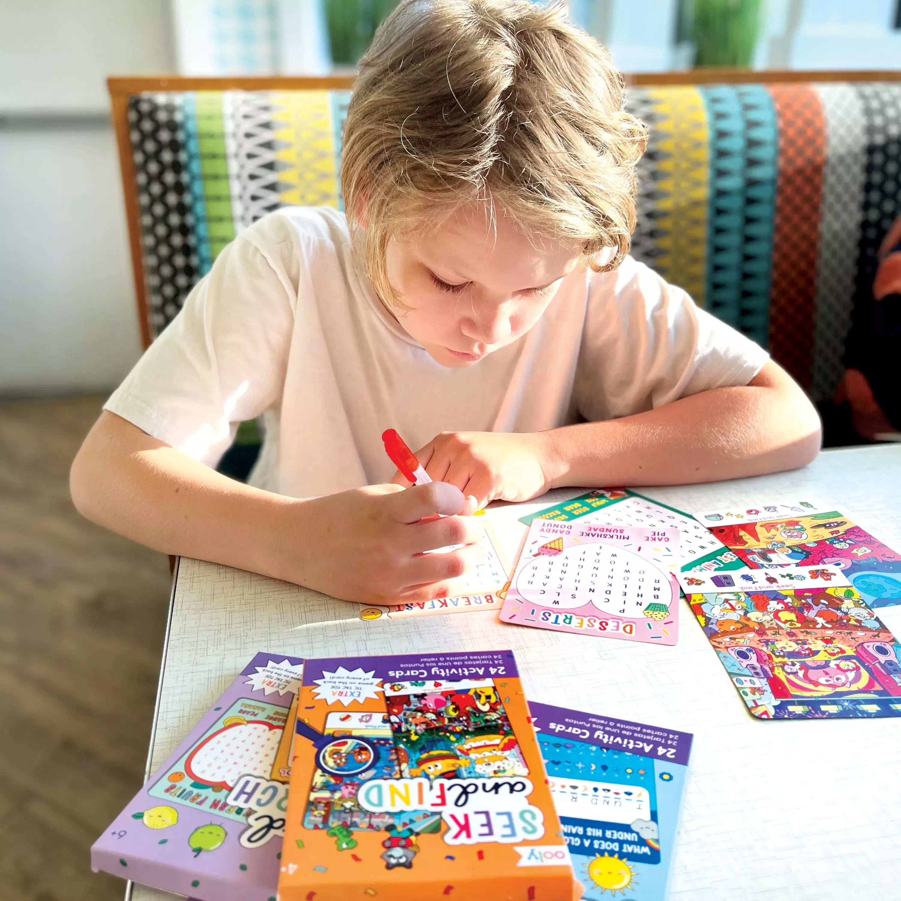 Kid in restaurant writing in OOLY Word Search Activity Card set